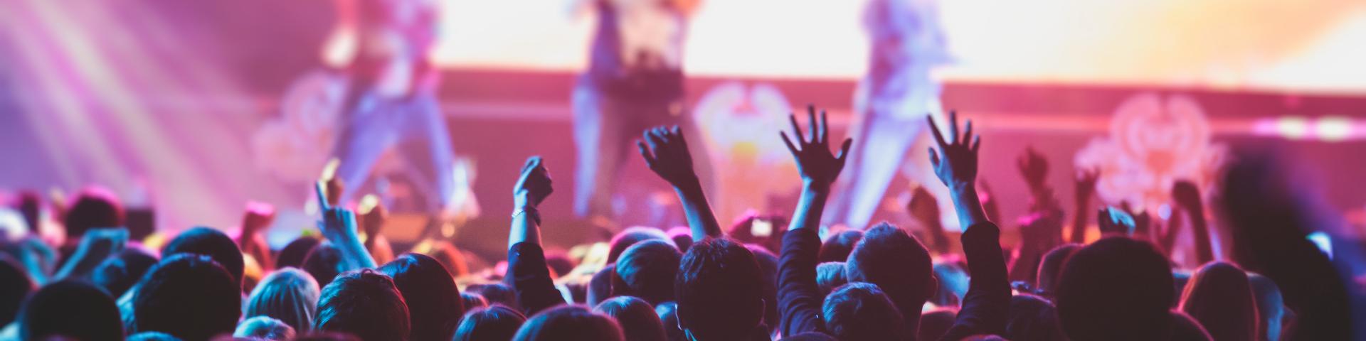 A crowd at a concert with lighting on the performers