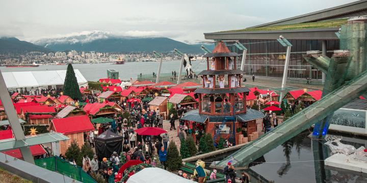 Photo of booths at the Vancouver Christmas Market overlooking the skyline of mountains at Jack Poole Plaza in Coal Harbour