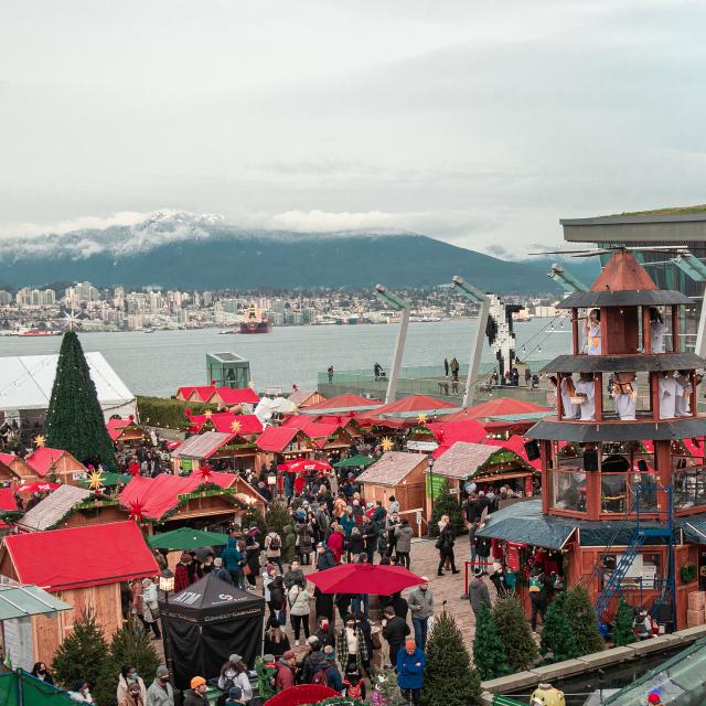 Photo of booths at the Vancouver Christmas Market overlooking the skyline of mountains at Jack Poole Plaza in Coal Harbour